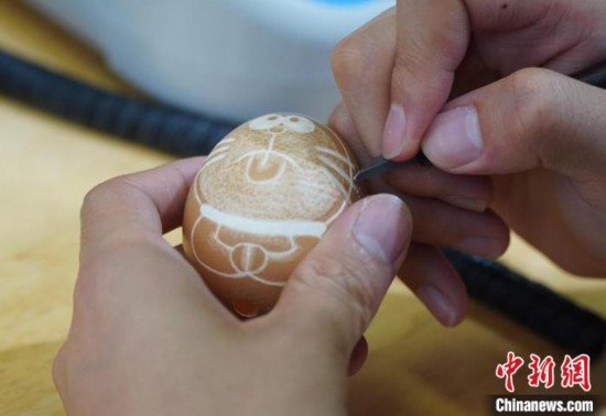 圖為學(xué)生們正在蛋殼上雕刻卡通圖案?！⒂裉?攝